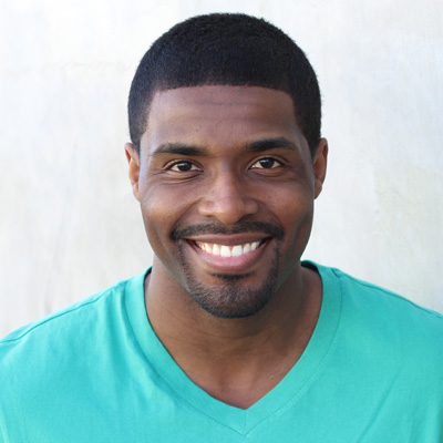 An elderly couple sitting close together, smiling and posing for the camera.