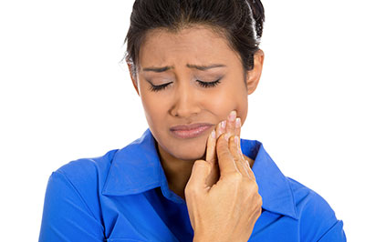 The image shows a woman with her eyes closed, holding her nose and looking upwards with an expression of concern or discomfort.