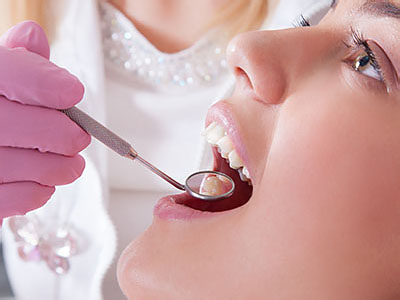 A dental professional is performing a procedure on a patient s mouth, using instruments and wearing protective gloves.