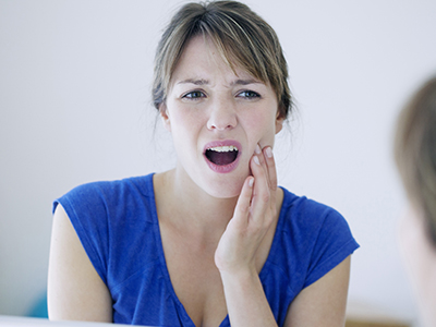 A young woman with a concerned facial expression, holding her hand to her mouth, possibly in disbelief or surprise.